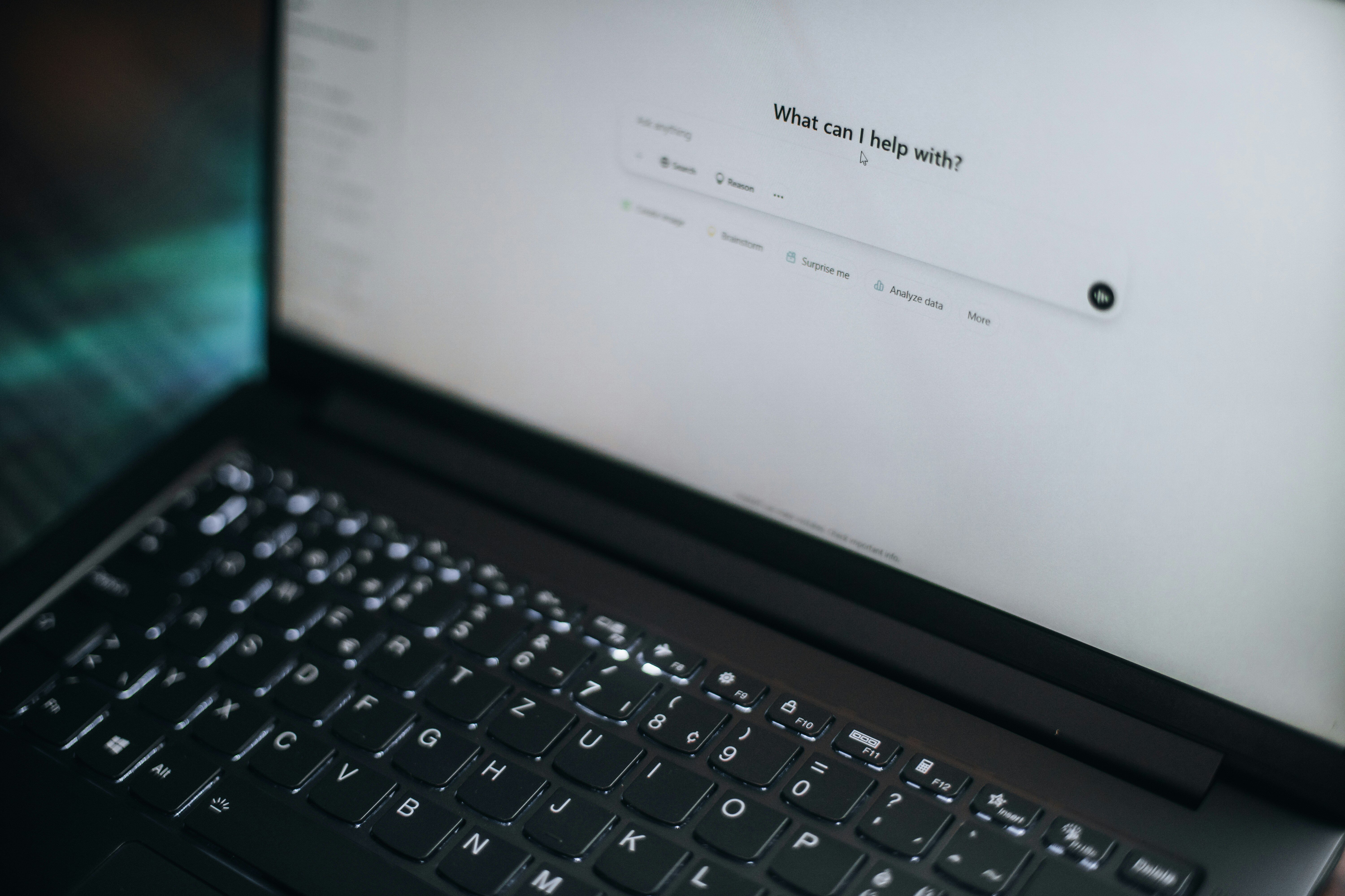 AI chat interface on a laptop screen asking “What can I help you with?”