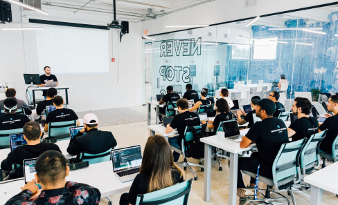 Students learning in a classroom at BrainStation Miami, facing the instructor and projector.