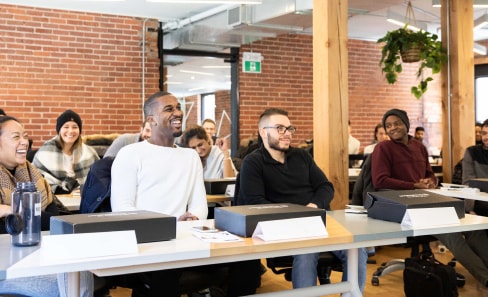 Coding bootcamps Toronto students smiling and sitting in a classroom for their first lesson.