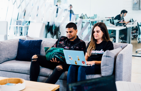 Students sitting on a couch, learning how to code in BrainStation Miami's collaborative space.